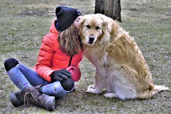 Une propriétaire de chien assise avec son chien. Comment apprendre le « assis » à son chien?